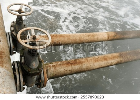 Rusty valves control water flow in an old treatment plant, showcasing the essential process of water purification along the riverbank.