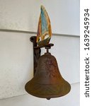 Rusty vintage bell with sailboat atop.