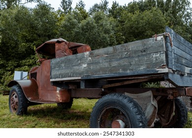 A rusty, vintage truck sits abandoned in a grassy field, showcasing its weathered metal and nostalgic charm, blending with the rural and rustic countryside environment - Powered by Shutterstock