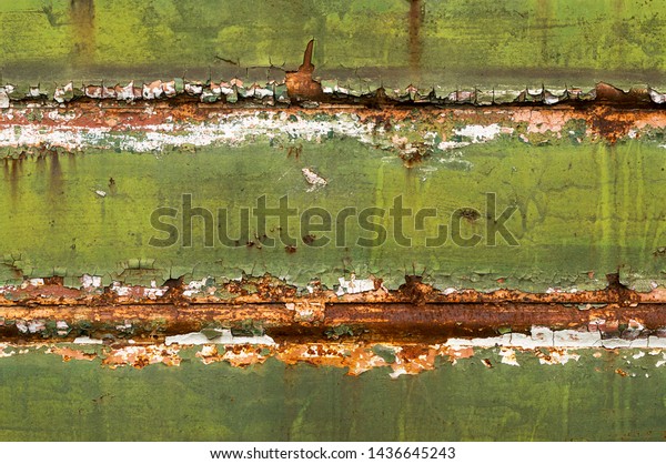 Rusty wall of the\
freight railway car. Metal surface with peeling green paint and\
rust. Grunge texture\
close-up
