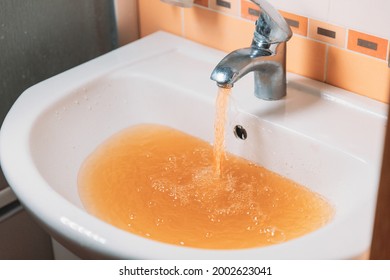 Rusty Water Pours From Tap. Water Pollution. Global Environment.