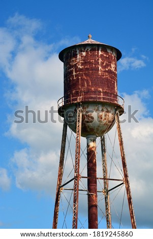 A rusty water tower with pealing paint and clouds in the background in Tarboro North Carolina.