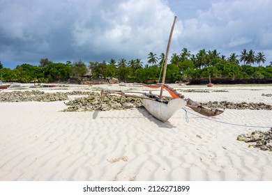Rusty wooden boat banka anchored at beach. Tropical low tide landscape with sailboats. Nautical vessel near palm tree coast, Africa, Zanzibar. Traditional transportation. Marine travel. 