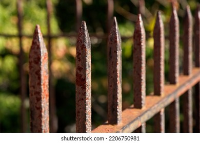 Rusty Wrought Iron Picket Fence Corner In Low Angle Sunlight Selective Focus On One Picket.