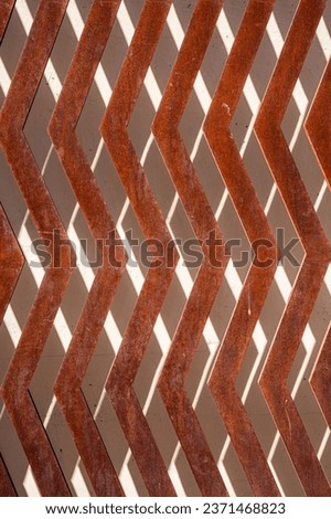 rusty zig zag metal in front of a stucco wall with shadows