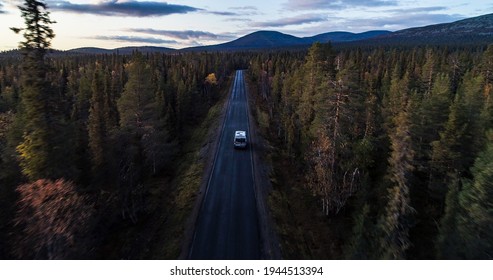 RV in autumn color forest, Aerial drone shot of a Camper van in foliage woods, moving towards Ounastunturit fells, sunny, autumn evening, in Lapland