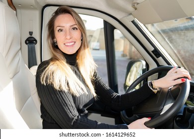 RV Camper Trailer Travel Woman Driving Motor Home Camping Van Tourist Driver Smiling Out Window Of Front Driver Seat In Vanlife