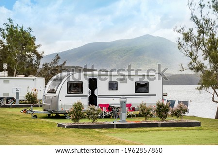 RV caravan camping at the caravan park on a peaceful lake with mountains on the horizon. Camping vacation family travel concept