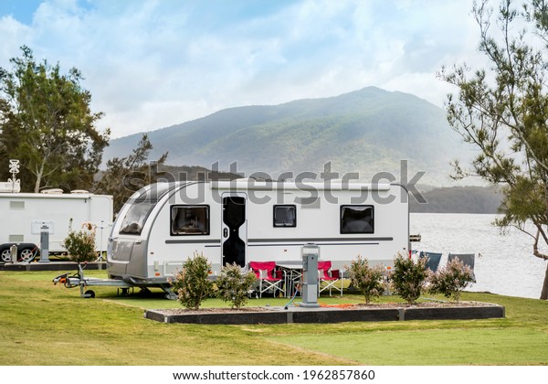 RV caravan camping at the caravan park on a
peaceful lake with mountains on the horizon. Camping vacation
family travel concept