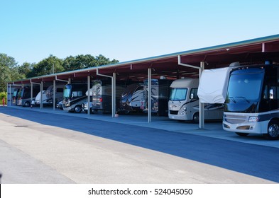 RV Recreational Vehicle Storage Parking Covered Garage Filled With Many New Looking RVs And Trailers.