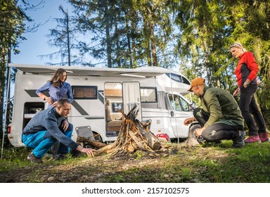 RV Road Trip Vacation with Friends. Two Caucasian Couples Hanging Around Campfire Next to Their Motorhome Camper Van. Dry Camping in a Forest.