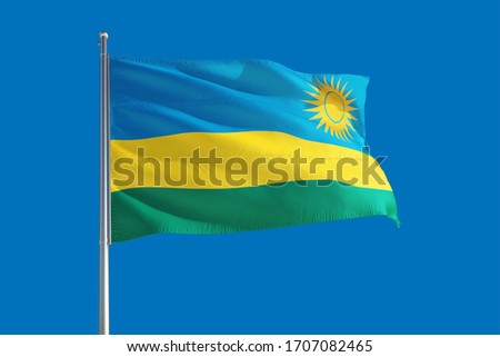 Rwanda national flag waving in the wind on a deep blue sky. High quality fabric. International relations concept.