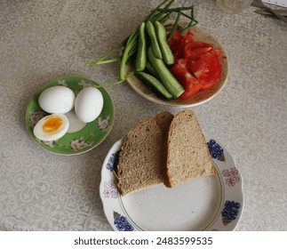 Rye bread, boiledeggs, slices of tomato and cucumber on three saucers