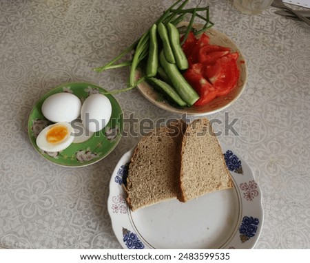 Rye bread, boiledeggs, slices of tomato and cucumber on three saucers