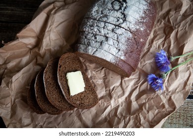 Rye bread with butter on a kraft paper with a linen napkin with cornflowers. Bread hunk - Shutterstock ID 2219490203