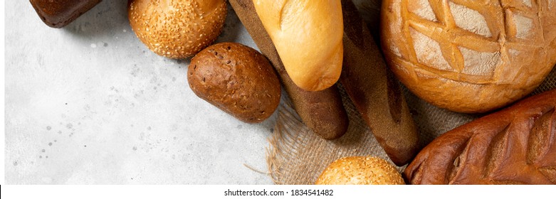 Rye and wheat bread of different shapes on a light gray table. Top view. Copyspace. Banner