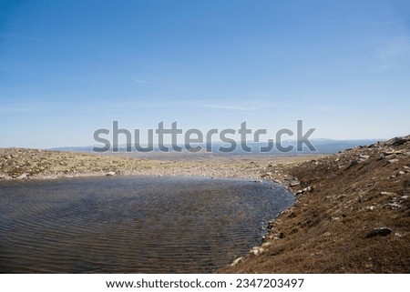 rystal clear water in a mountain lake, the bottom is visible, the shore smoothly turns into a hill formation, a clear summer day in Norway