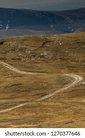 S Curve Path Through The Mountain With Orange Grass And Blue Sky In The Background