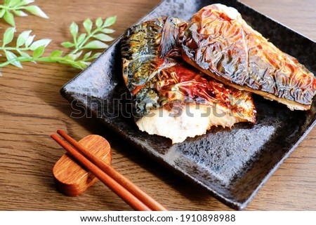 Saba no sio yaki (grilled mackerel). A traditional Japanese grilled fish dish. Two fillets on a black plate.