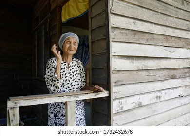 Sabah, Malaysia – May 16, 2020: An Elderly Woman's Sits In Front Of Her House. Back To Kampung For Hari Raya Theme.