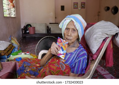 Sabah, Malaysia – May 16, 2020: An Elderly Woman's Sits In Front Of Her House. Back To Kampung For Hari Raya Theme.