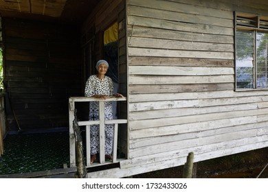 Sabah, Malaysia – May 16, 2020: An Elderly Woman's Sits In Front Of Her House. Back To Kampung For Hari Raya Theme.