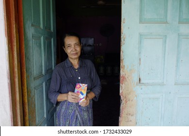 Sabah, Malaysia – May 16, 2020: An Elderly Woman's Sits In Front Of Her House. Back To Kampung For Hari Raya Theme.