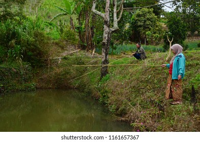 Sabah/Malaysia_Sep 19 2017: An Old Couple Fishing At The Side Of The Pool At Kundasang With Their Lovely Cat.