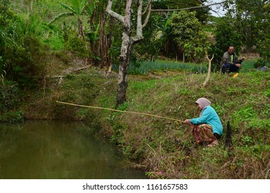 Sabah/Malaysia_Sep 19 2017: An Old Couple Fishing At The Side Of The Pool At Kundasang With Their Lovely Cat.