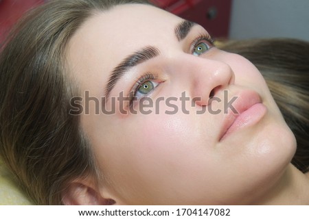 Sable style eyebrows concept. Close up portrait of young sensual model with clean skin, professional make up and beautiful green eyes, laminated eyelashes, tropical background with fern leaves.