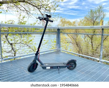 Sac, CA - April 2, 2021: Electric Scooter Parked Using A Kickstand Off A Bike Trail Near A River. 