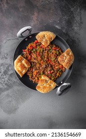 Sac kavurma or turkish meat with bread pita in a black iron pan on a dark background top view, copy space - Shutterstock ID 2136154669