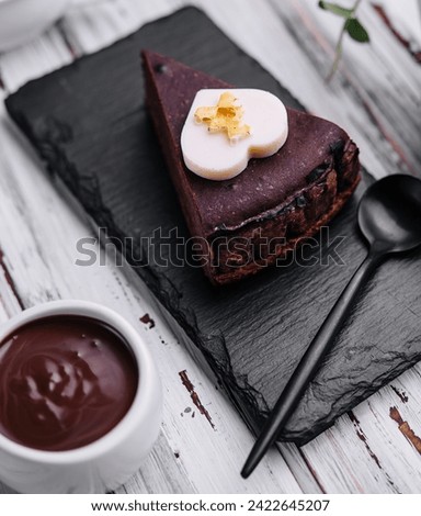 Sacher cake slice and chocolate cream on wood