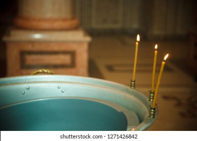 The sacrament of Orthodox Baptism, a font with holy water and lit candles in the temple