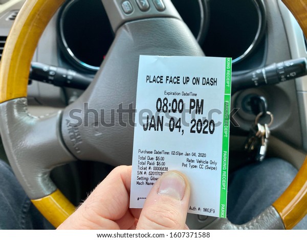 Sacramento, CA -\
January 4, 2020: Man holding a parking receipt that has to be\
placed on dash to show proof of payment to avoid getting a parking\
violation, inside a local state\
park.