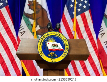 Sacramento, CA - March 8, 2022: Seal of the Governor of the State of California on a wood podium with American and California flags alternating behind in front of a blue curtain.