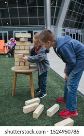 Sacramento, CA - September 28, 2019: Two Boys Playing With Large Jenga Wood Blocks On Artificial Turn Outside Of Golden One Arena.