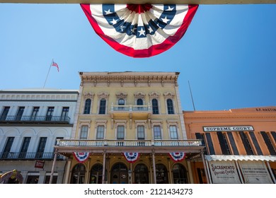 Sacramento, California, USA - 2021 July 5: Facades Of Historic Houses With American Flag Bunting In Backlight In Foreground