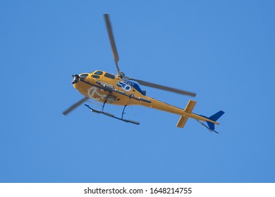 Sacramento, California / USA - November 2, 2019: Helicopter For Channel 7 ABC News, With Nose Mounted Television Camera, Speeding Through Blue Sky. Gold Colored Aircraft With Blue Logo