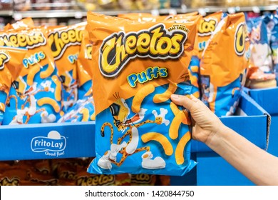 Sacramento, CA/USA 06/07/2019   Shoppers Hand Holding A Bag Of Cheetos Brand Puff Cheese Snacks In A Supermarket Aisle