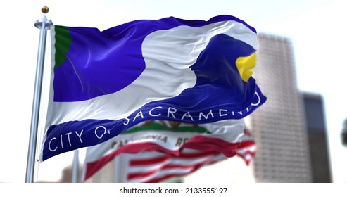 Sacramento city flag waving in the wind with California state and United States national flags blurred in background. Sacramento municipal flag