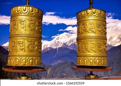 Sacred Buddhist prayer wheel with beautiful mountain landscape background of sikkim himalayas. Translation : “Om mani padme hum” (meaning “jewel in the lotus”