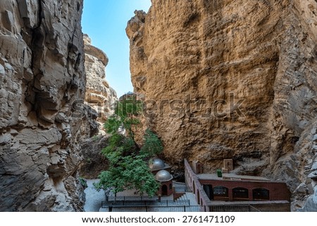 Sacred complex with two domes nestled between towering canyon walls at the historic Ashabi Kahf, a site of religious pilgrimage in Nakhchivan, Azerbaijan