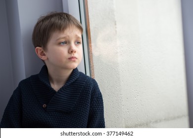 Sad 7 Years Boy Child Looking Out The Window. Rainy Day