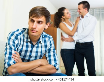Sad adult ex-lover watching girlfriend leaving him for another man indoors