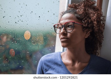 Sad African American Girl Looking Out Of The Window On Rainy Weather