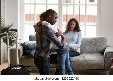 Sad african american kid girl hugging dad upset by father leaving, daddy with suitcase saying good bye embracing little daughter, kid and parents divorcing, black family shared child custody concept