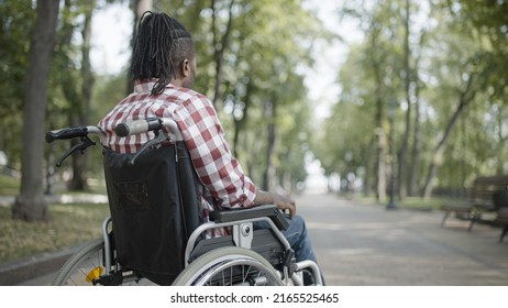 Sad African American man in wheelchair sitting alone in park, suffering loneliness