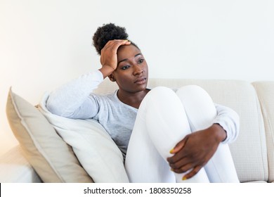 Sad African American Woman With Depression Sitting On Sofa. Lonely Stressed Upset Young Black Girl Thinking Of Psychological Problem Thinking Regret About Mistake