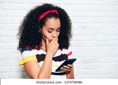 Sad African American Woman Reading Bad News On Cell Phone. Black Girl Showing Sadness And Desperation For Message On Mobile Telephone. Hispanic Person With Smartphone